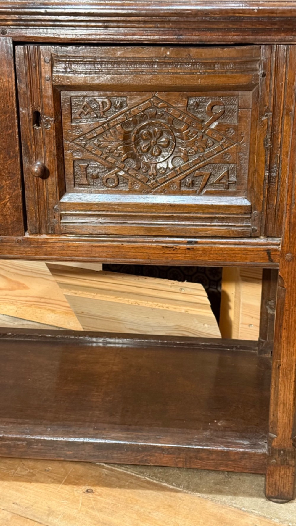 A 17th-century dark oak livery cupboard featuring a single door carved with initials and dated 1674, supported on upright legs with an open lower shelf. View III