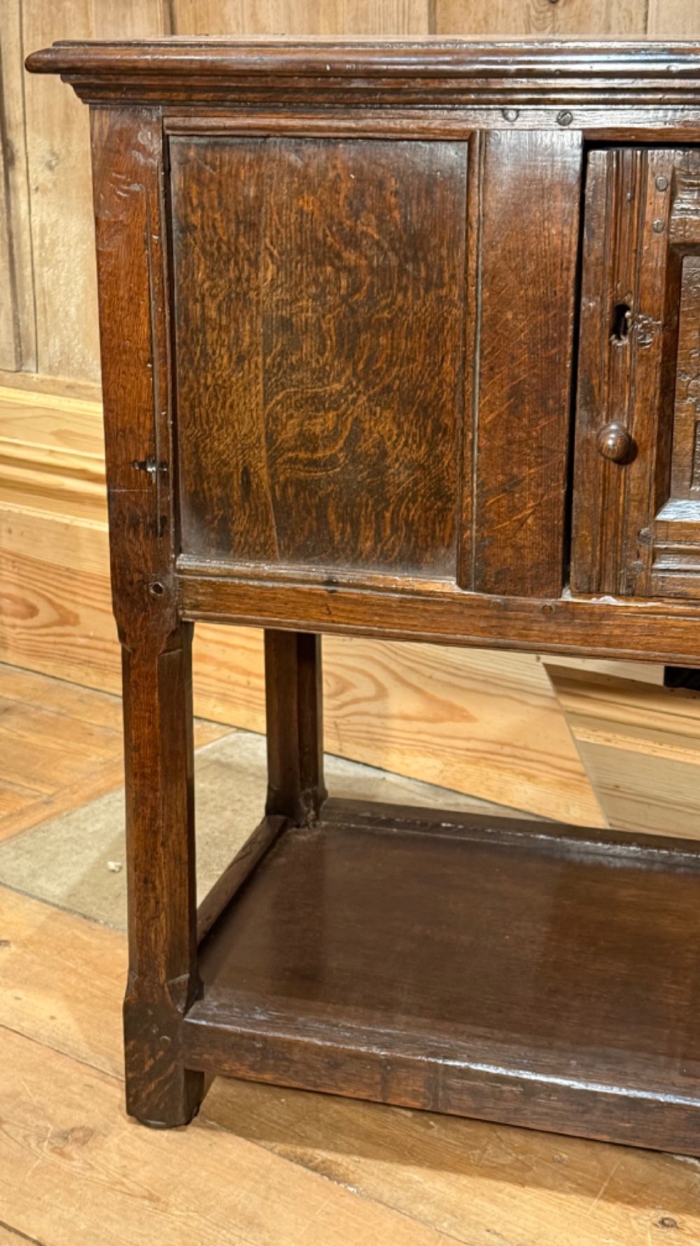 A 17th-century dark oak livery cupboard featuring a single door carved with initials and dated 1674, supported on upright legs with an open lower shelf. View V