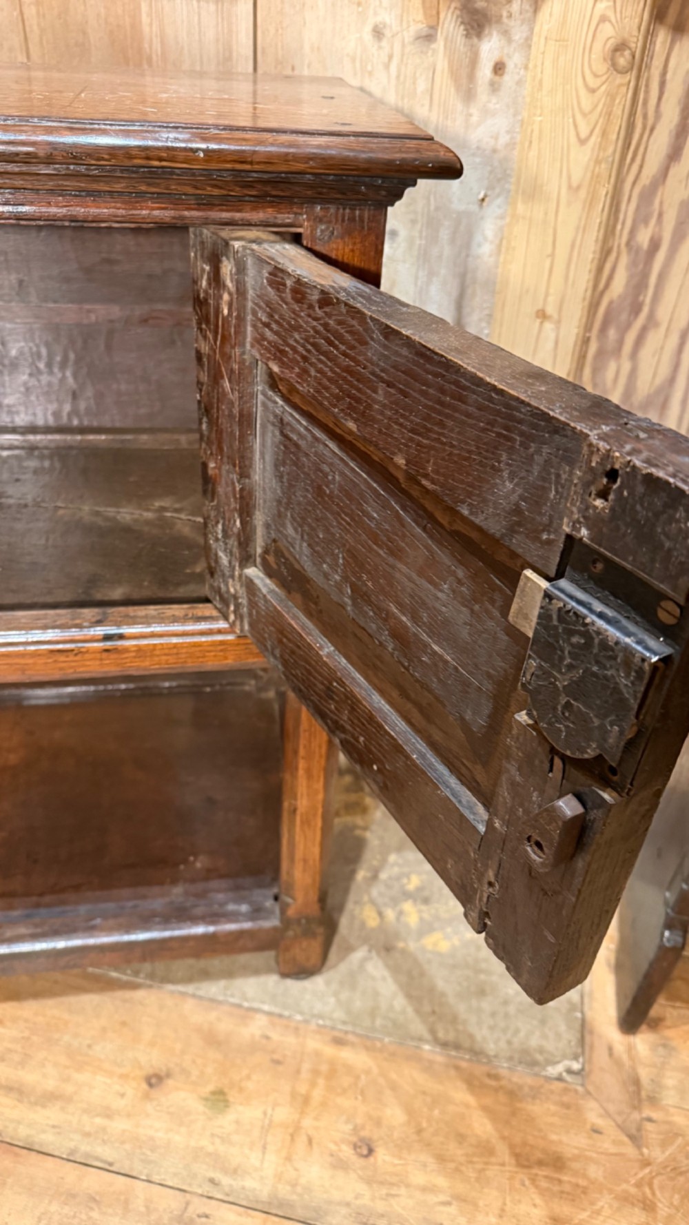 A 17th-century dark oak livery cupboard featuring a single door carved with initials and dated 1674, supported on upright legs with an open lower shelf. View VI