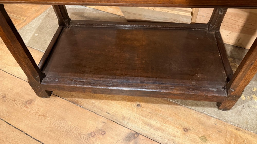 A 17th-century dark oak livery cupboard featuring a single door carved with initials and dated 1674, supported on upright legs with an open lower shelf. View VIII