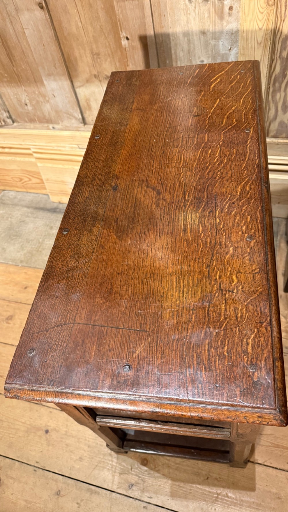 A 17th-century dark oak livery cupboard featuring a single door carved with initials and dated 1674, supported on upright legs with an open lower shelf. View IX