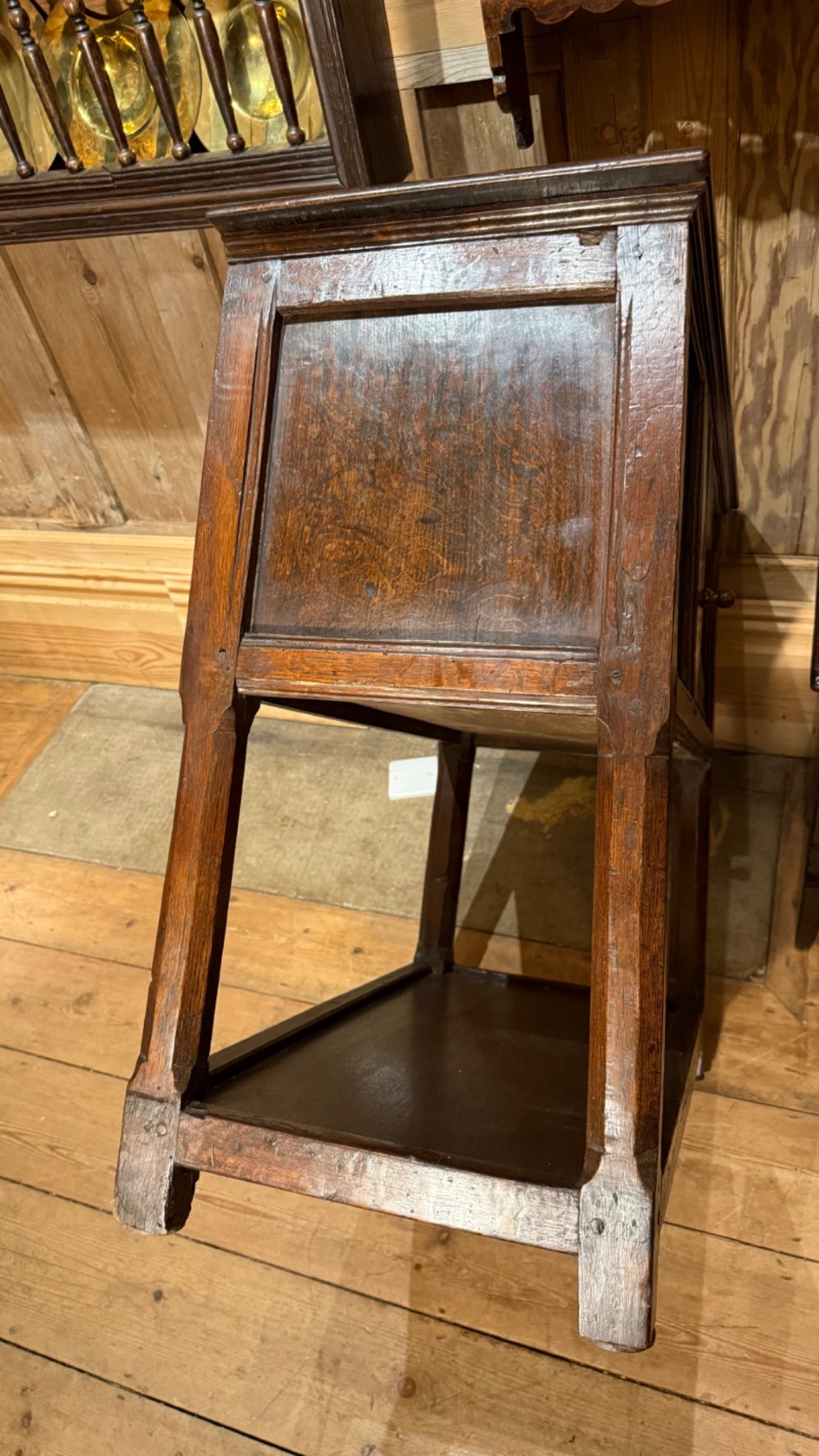 A 17th-century dark oak livery cupboard featuring a single door carved with initials and dated 1674, supported on upright legs with an open lower shelf. View XV
