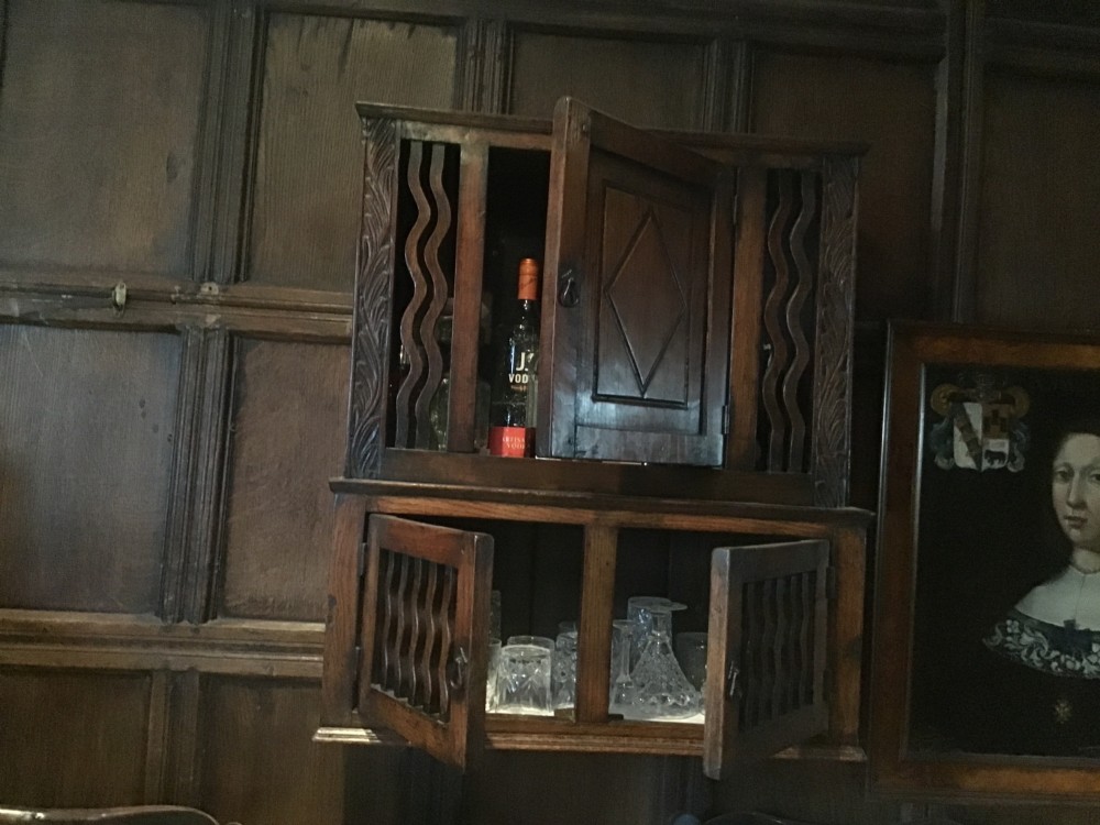 An 18th-century carved oak wall cabinet featuring a central door with a carved diamond motif flanked by wavy vertical slats and a lower two-door slatted cupboard. View X