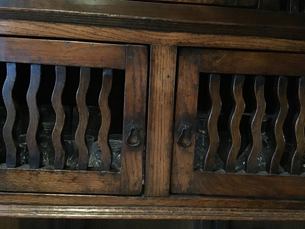 An 18th-century carved oak wall cabinet featuring a central door with a carved diamond motif flanked by wavy vertical slats and a lower two-door slatted cupboard. View XI
