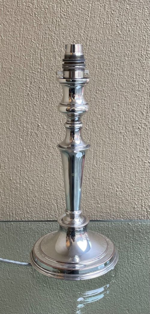 A polished silver-plated table lamp shaped as a classical candlestick with a beaded circular base and turned stem. View II