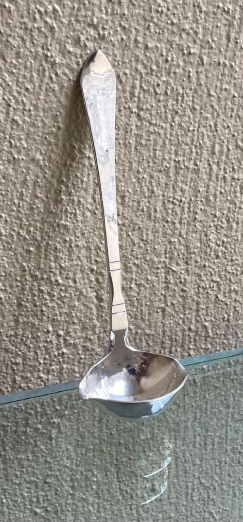 A sterling silver Georg Jensen sauce ladle with a side pouring spout and a slender handle with linear accents. View II