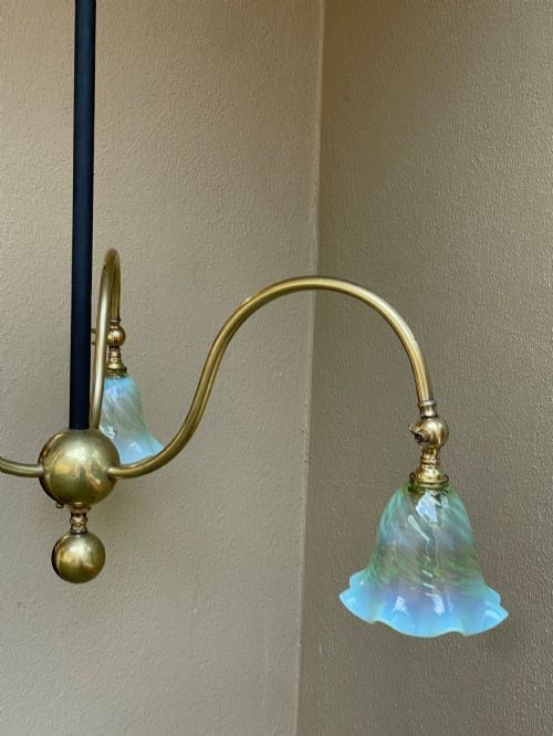 An Arts and Crafts style brass three-arm ceiling light featuring downward-curving swan-neck arms holding fluted opalescent green glass shades suspended from a central stem. View III