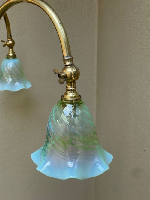 An Arts and Crafts style brass three-arm ceiling light featuring downward-curving swan-neck arms holding fluted opalescent green glass shades suspended from a central stem. View IV