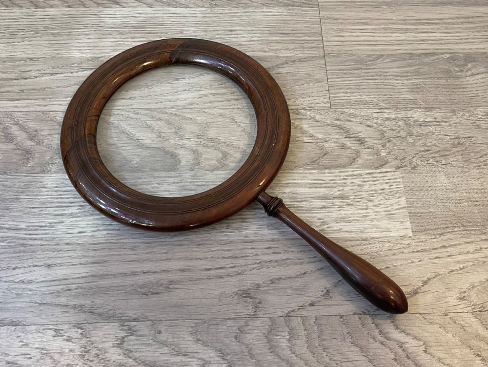A large Regency rosewood hand held magnifying gallery glass. The glass lens surrounded by a circular border and turned handle. 
