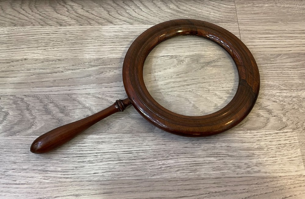 A large Regency rosewood hand held magnifying gallery glass. The glass lens surrounded by a circular border and turned handle.  View II