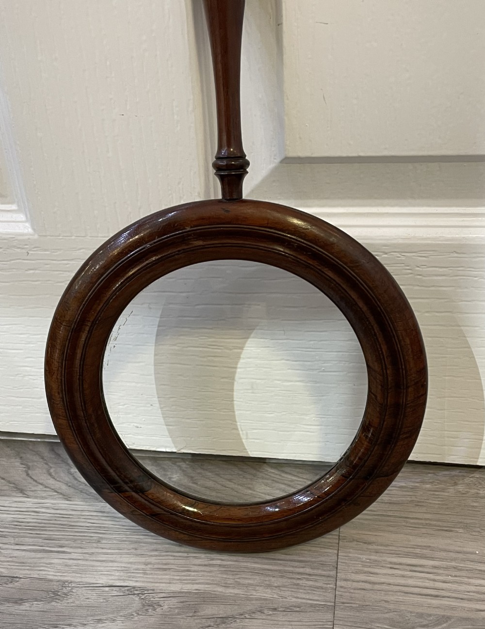 A large Regency rosewood hand held magnifying gallery glass. The glass lens surrounded by a circular border and turned handle.  View V