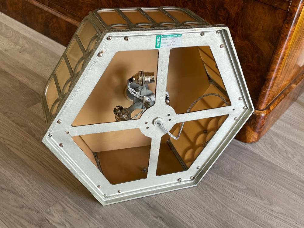 An Art Deco hexagonal flush ceiling light featuring frosted amber glass panels set within a scalloped metal frame and a central glass finial. View V
