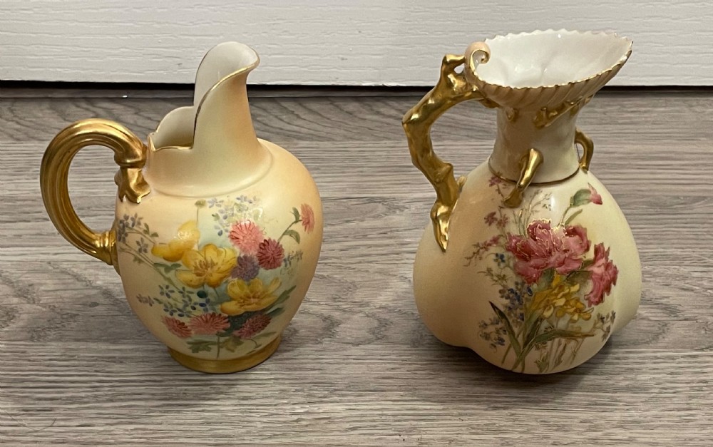 A pair of Victorian Royal Worcester porcelain jugs featuring a blush ivory ground, hand-painted floral sprays, and gilded handles. View II