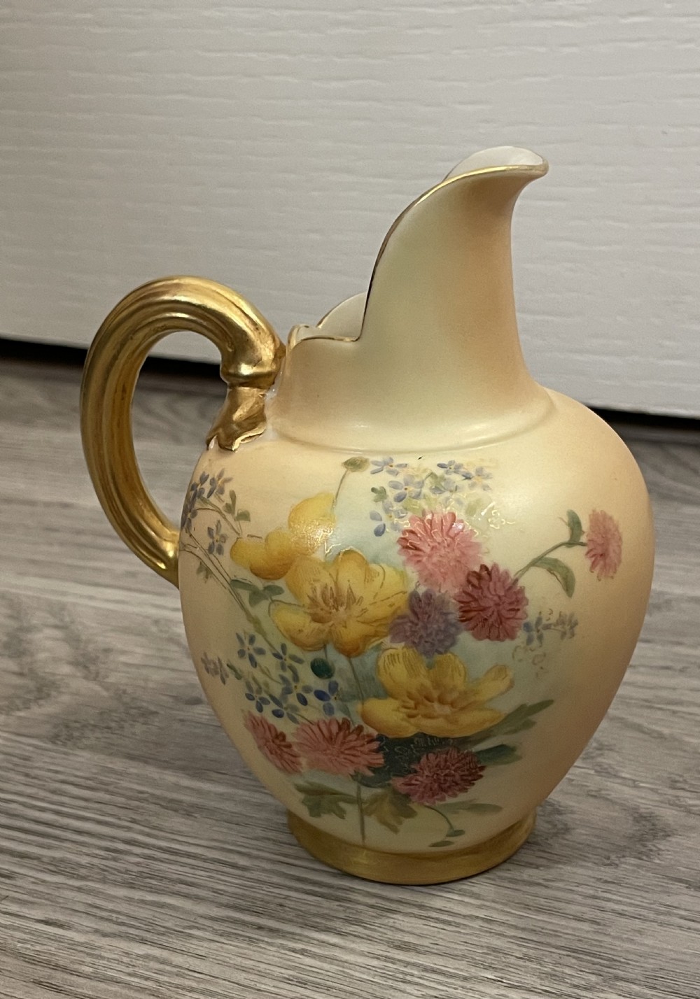 A pair of Victorian Royal Worcester porcelain jugs featuring a blush ivory ground, hand-painted floral sprays, and gilded handles. View III