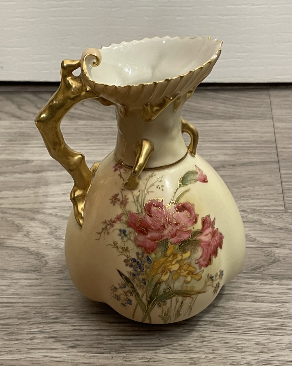 A pair of Victorian Royal Worcester porcelain jugs featuring a blush ivory ground, hand-painted floral sprays, and gilded handles. View VII