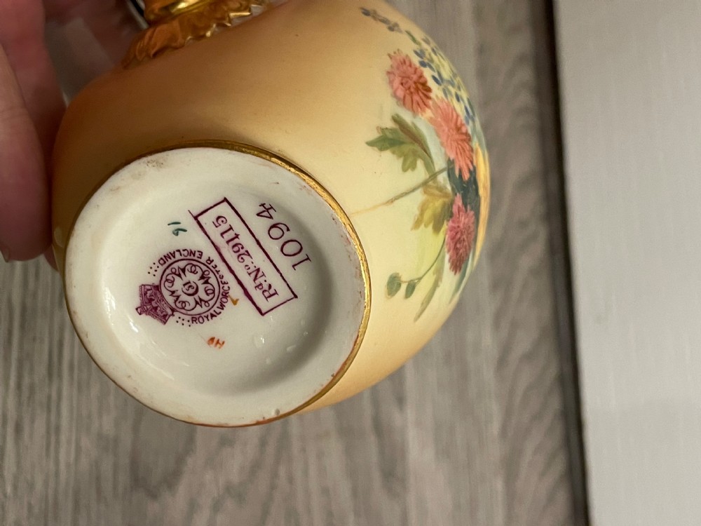 A pair of Victorian Royal Worcester porcelain jugs featuring a blush ivory ground, hand-painted floral sprays, and gilded handles. View VIII