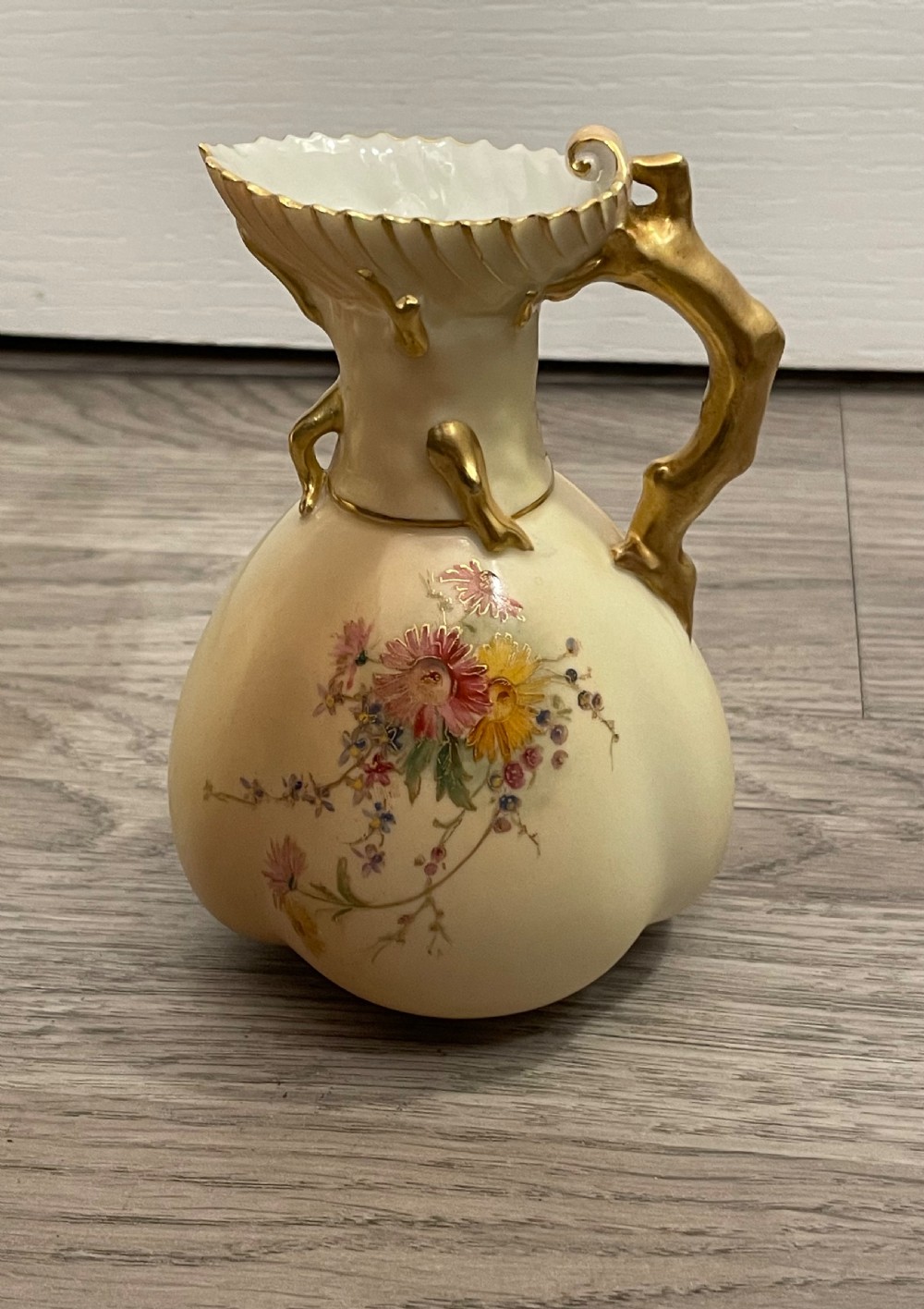 A pair of Victorian Royal Worcester porcelain jugs featuring a blush ivory ground, hand-painted floral sprays, and gilded handles. View IX