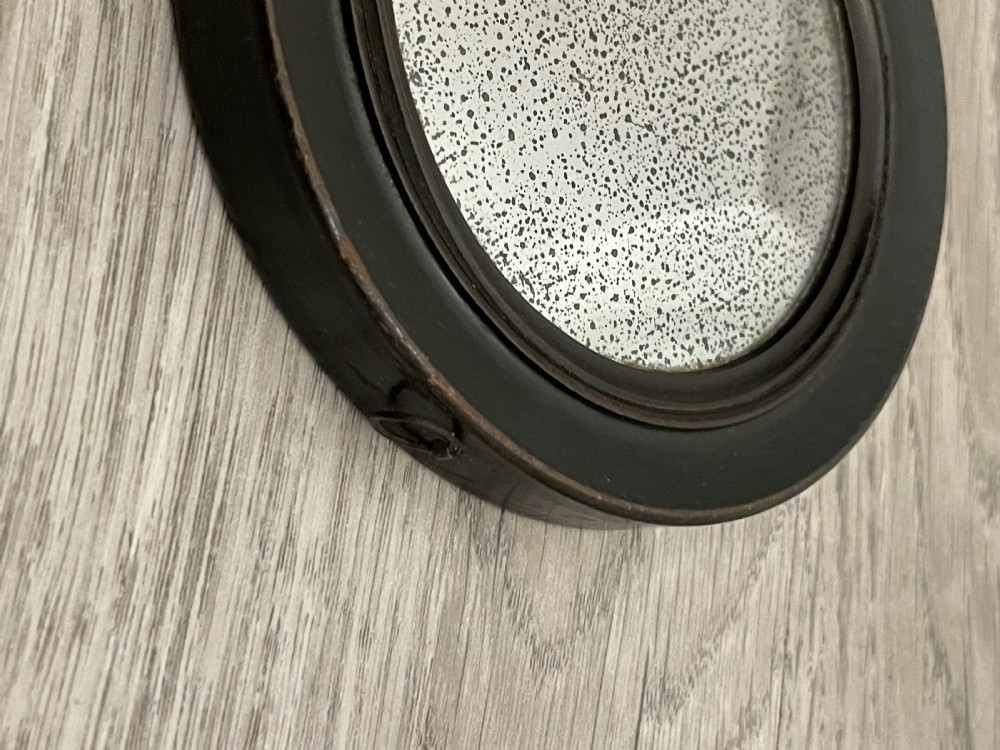 A circular double-sided Regency hand-held mirror featuring an ebonised turned wooden handle and original foxed glass plate. View V