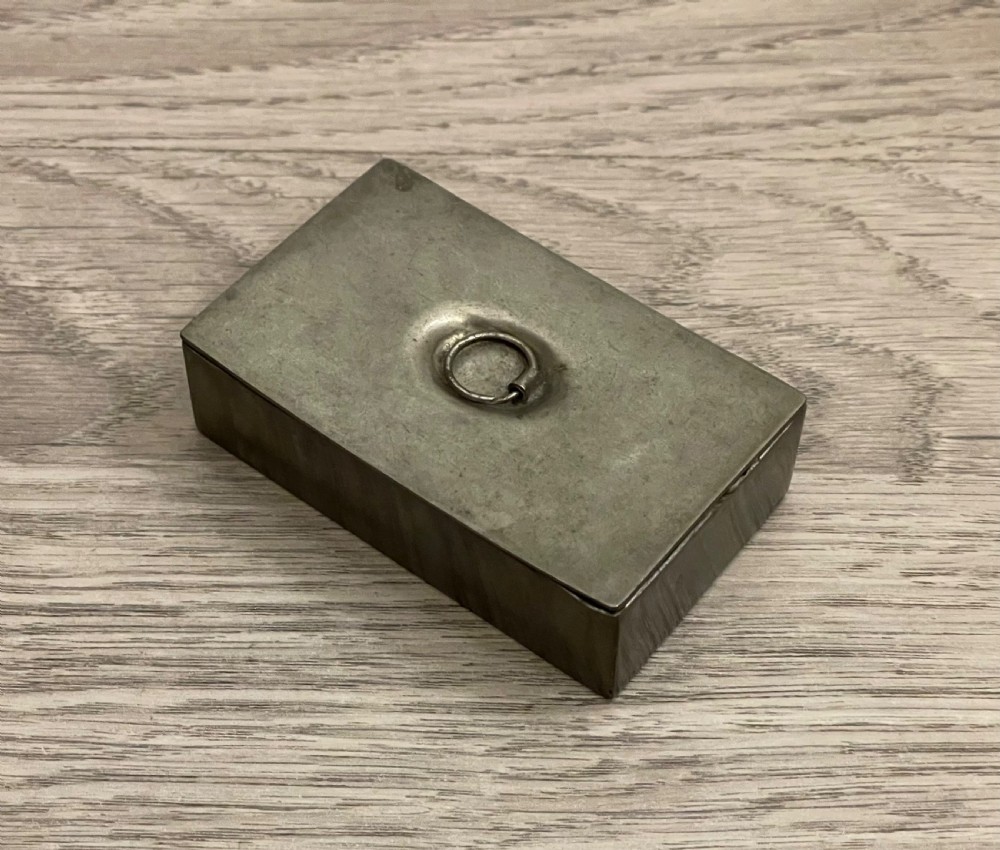 A rectangular 19th-century pewter snuff box featuring a flat hinged lid with a central recessed ring pull handle.