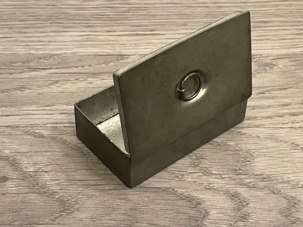 A rectangular 19th-century pewter snuff box featuring a flat hinged lid with a central recessed ring pull handle. View II