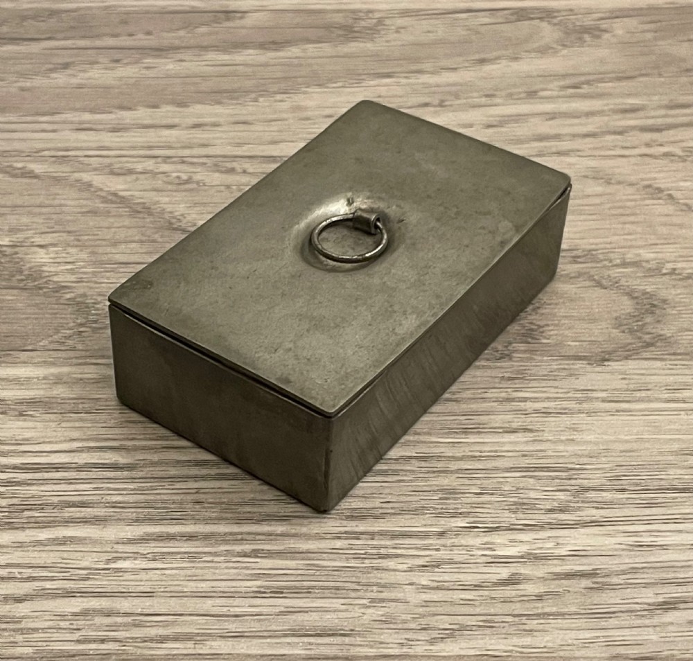 A rectangular 19th-century pewter snuff box featuring a flat hinged lid with a central recessed ring pull handle. View III