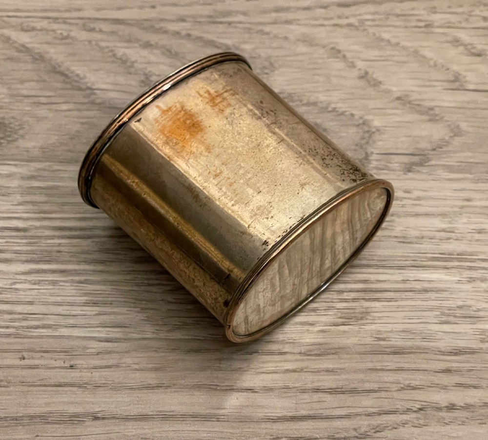 A cylindrical silver plated tea caddy featuring a repousse foliate patterned lid with a raised central finial. View V