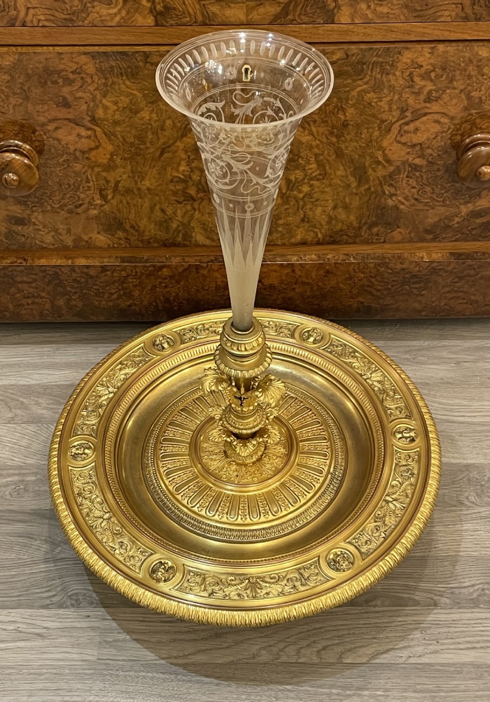 A nineteenth-century gilt bronze circular centrepiece tray decorated with relief borders supporting a central flared etched glass epergne vase.