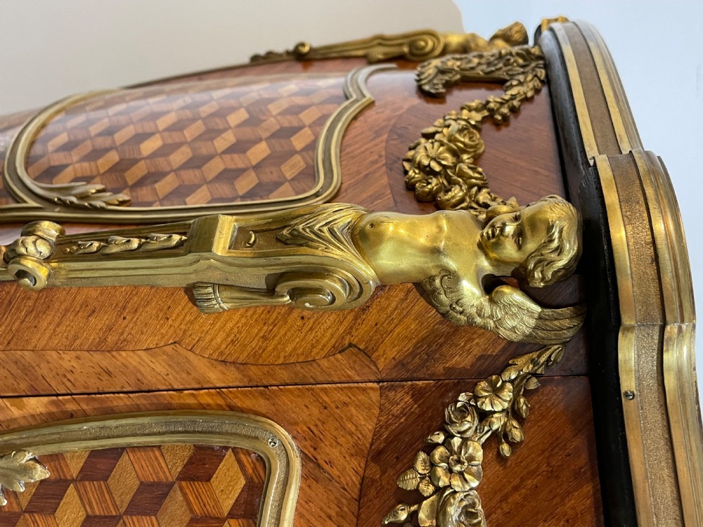 A French kingwood bedside cabinet featuring cube parquetry inlay, gilt ormolu mounts, floral garlands, and a shaped marble top. View VIII
