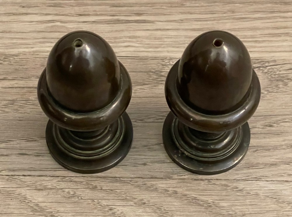 A pair of turned dark bronze spice shakers featuring acorn-form tops set upon circular stepped pedestal bases. View II