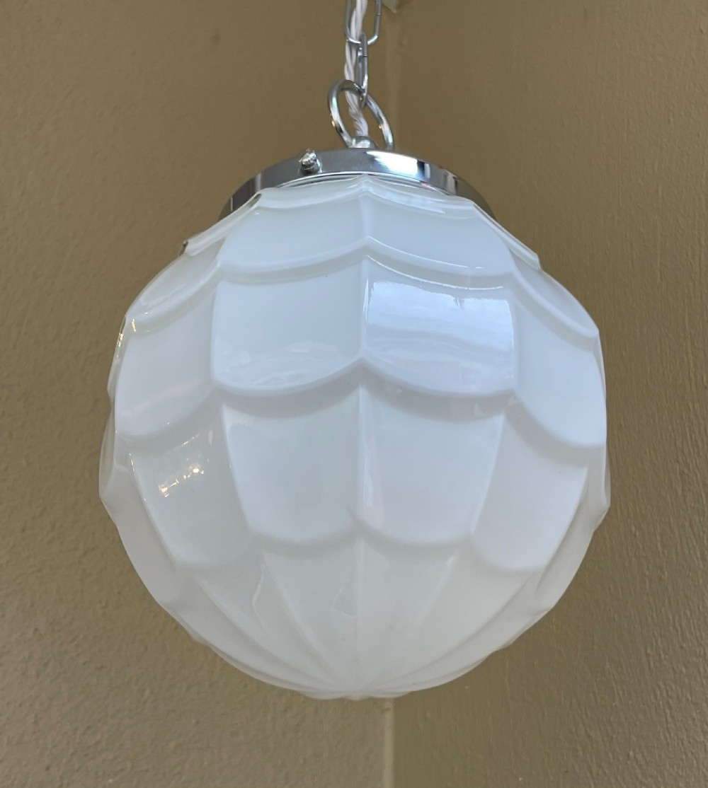 A white opaline glass spherical pendant light with a moulded fish scale texture, suspended by a chrome gallery and metal chain. View III