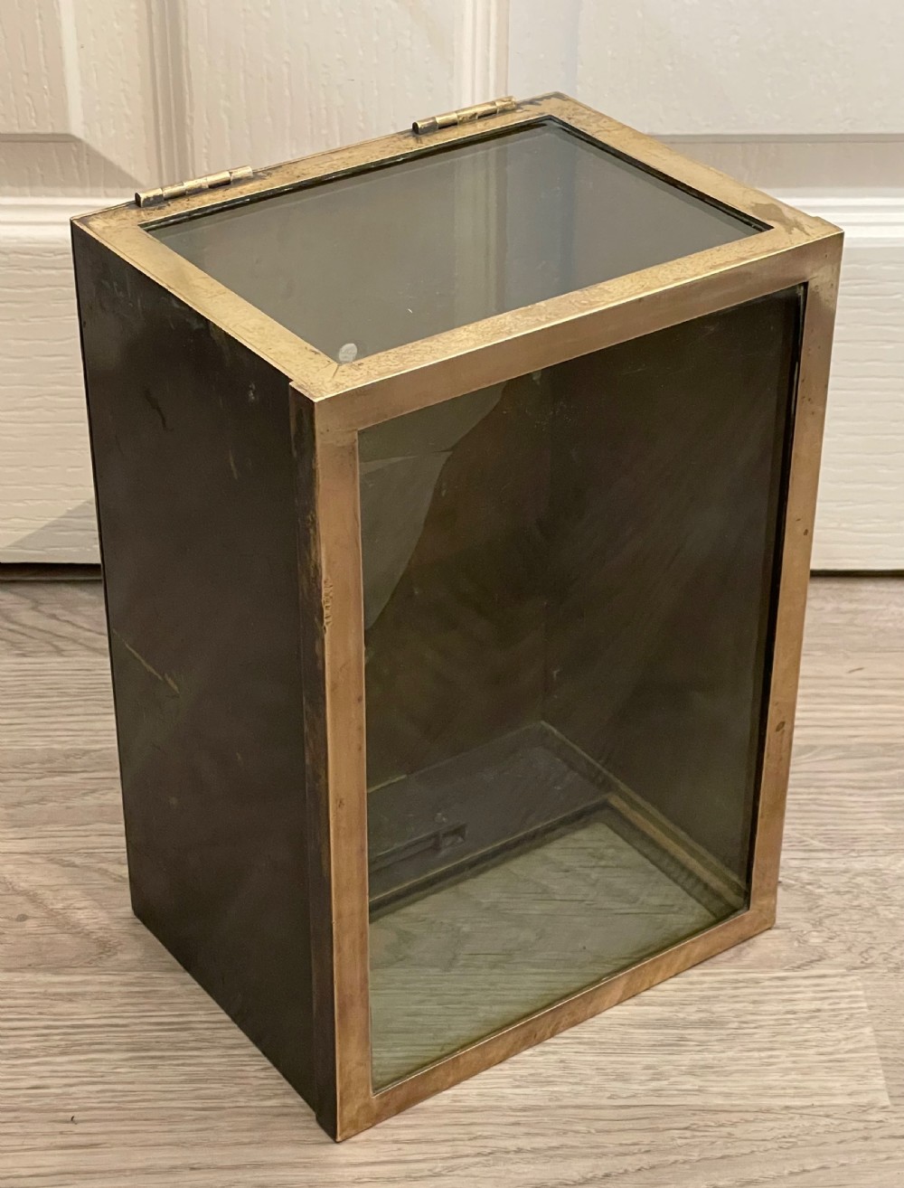 A rectangular patinated brass display case featuring a clear glass top, glazed front panel, and lower brass section with a built-in keyhole. View III