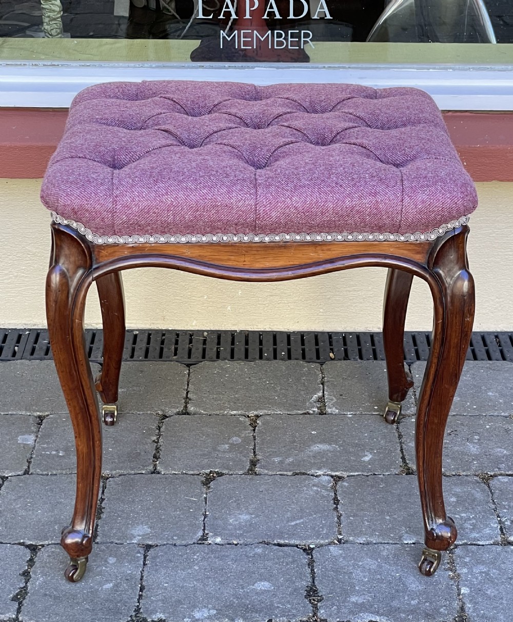 Victorian rosewood stool featuring button-tufted purple tweed upholstery, carved cabriole legs, and brass castors.