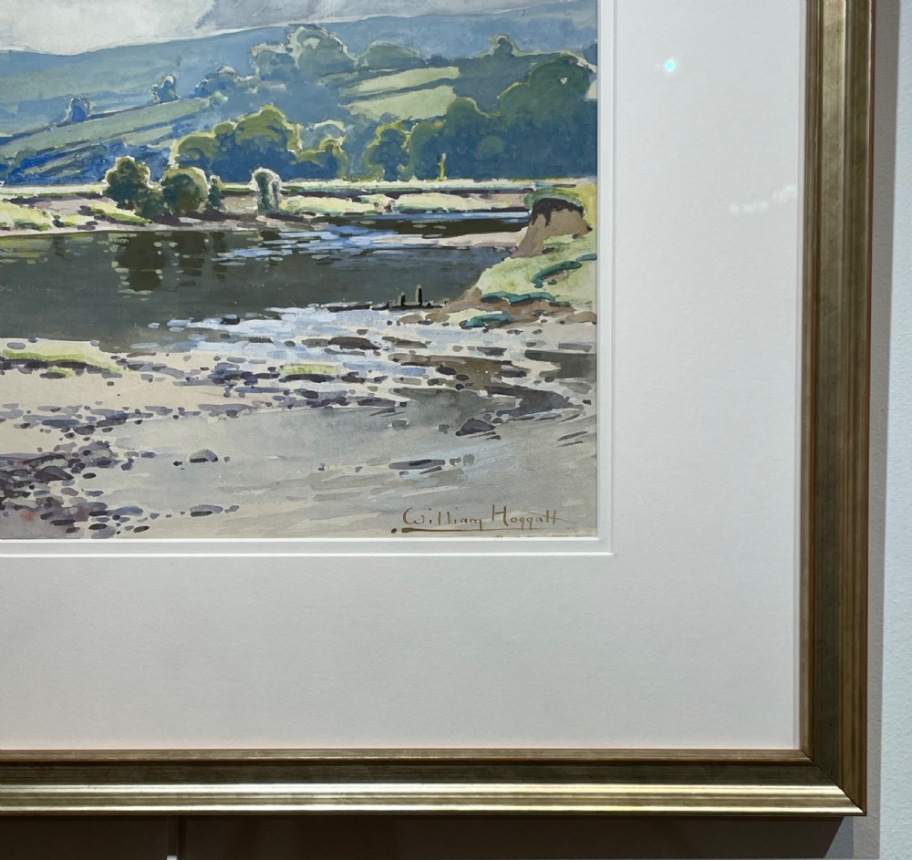A framed watercolour painting depicting a river and rolling green hills under a cloudy sky, housed in a cream mount and metallic gold frame. View IV