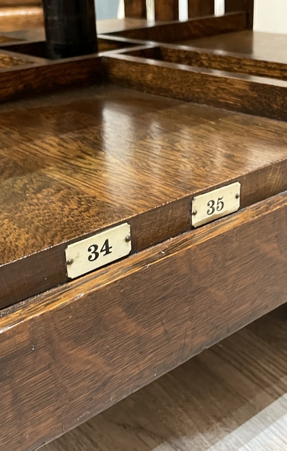 A multi-tiered Edwardian dark oak revolving bookcase with vertical side slats, upper gallery spindles, and small numbered tags along the shelf edges. View VI