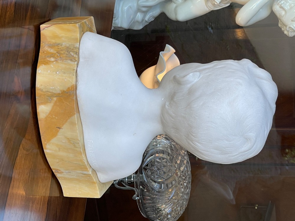 A white Carrara marble sculpture depicting the bust of a young boy, mounted on a yellow variegated marble base. View III