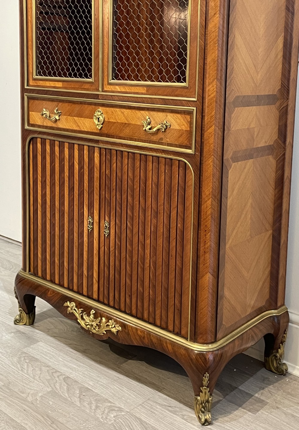 French kingwood cabinet featuring wire mesh upper doors, a marble top, gilt-bronze corner mounts, a central drawer, and reeded lower doors. View II
