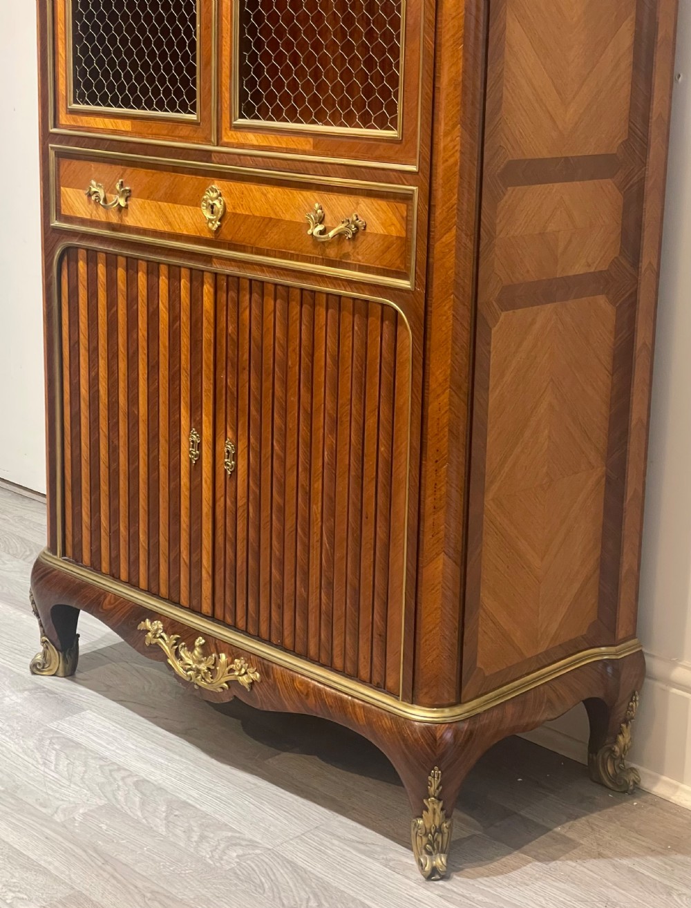 French kingwood cabinet featuring wire mesh upper doors, a marble top, gilt-bronze corner mounts, a central drawer, and reeded lower doors. View XII