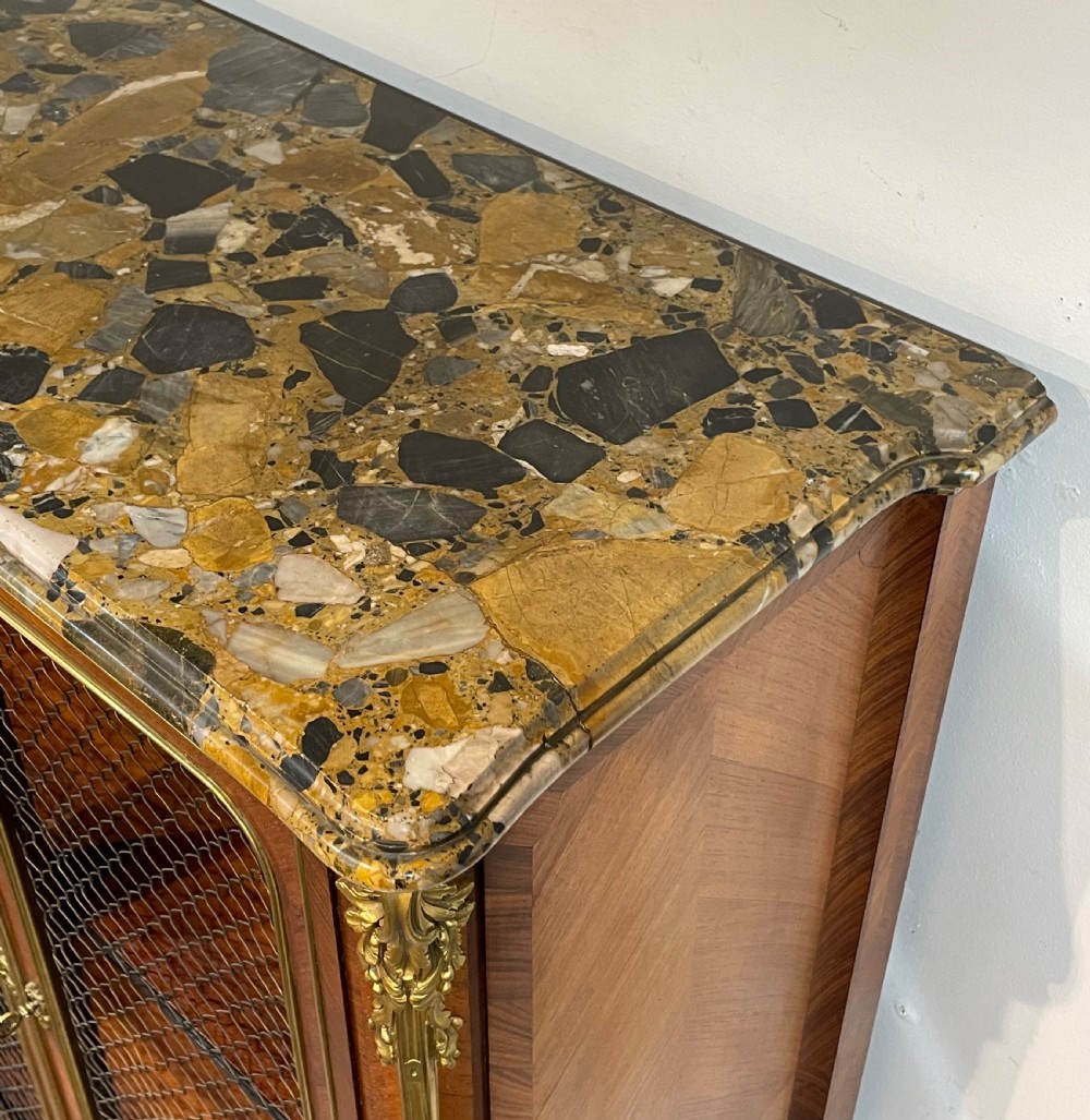 French kingwood cabinet featuring wire mesh upper doors, a marble top, gilt-bronze corner mounts, a central drawer, and reeded lower doors. View XIV