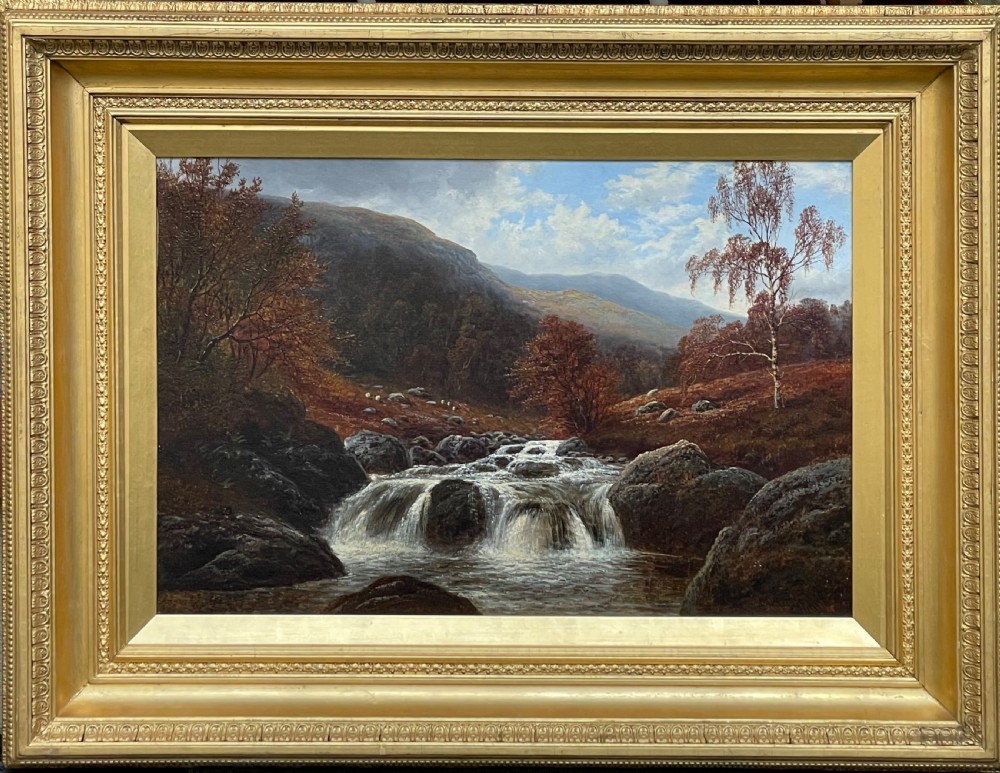 A framed Victorian oil painting depicting a cascading waterfall through a rocky North Wales stream surrounded by autumn trees and distant hills.