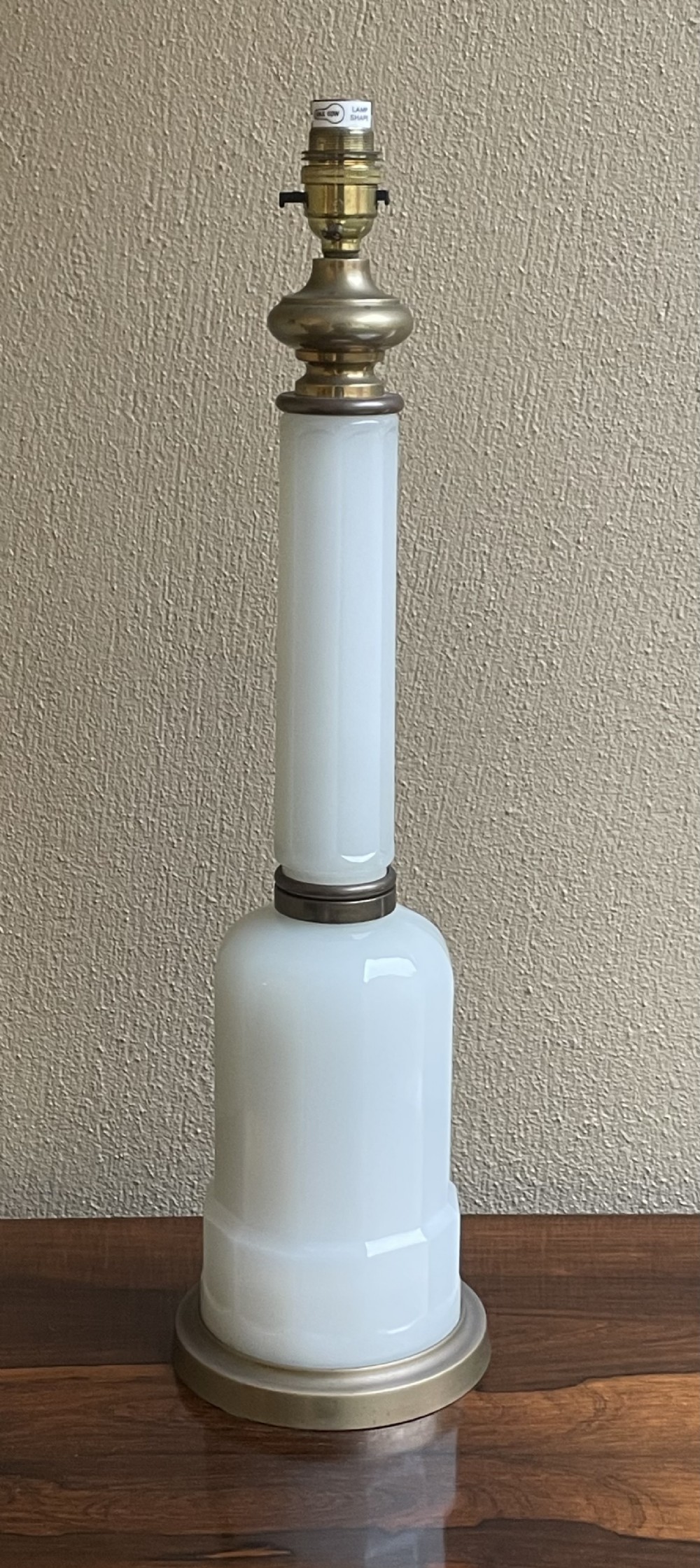 An early 20th-century table lamp base featuring a white opaline glass column set above a rounded glass lower body and circular brass base.