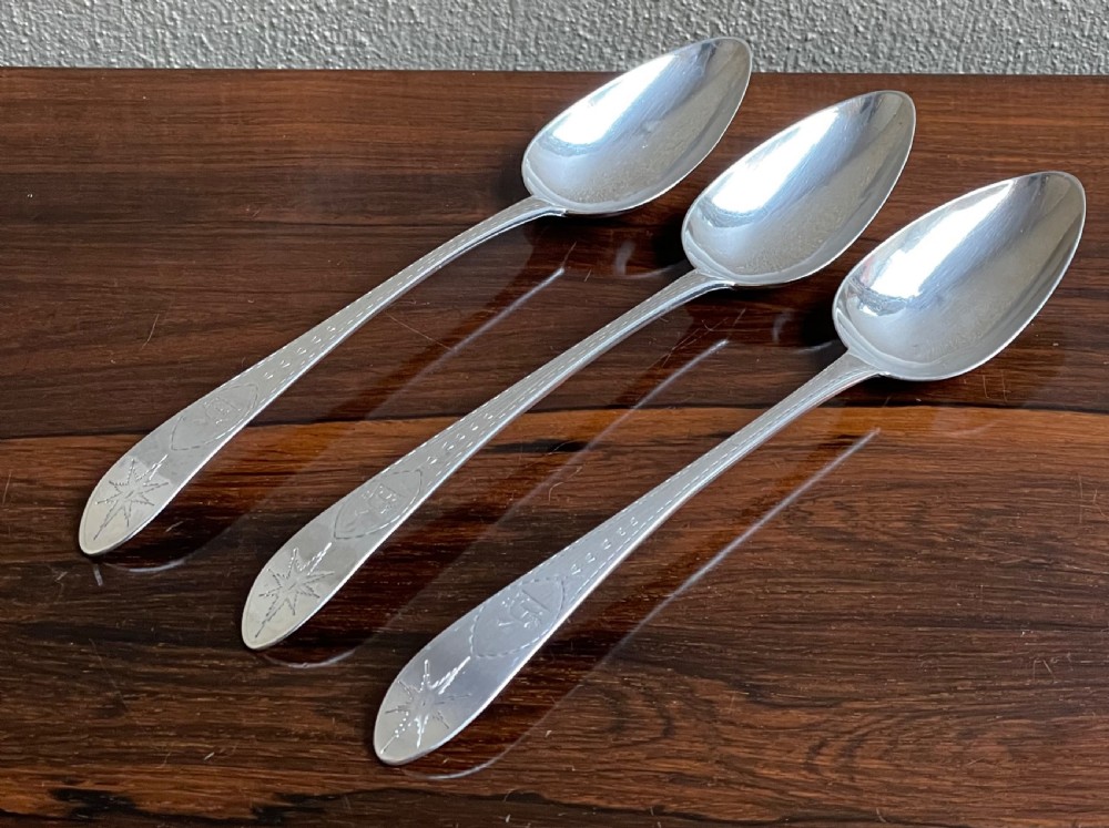 A set of three Georgian Irish sterling silver serving spoons featuring bright-cut engraved handles.