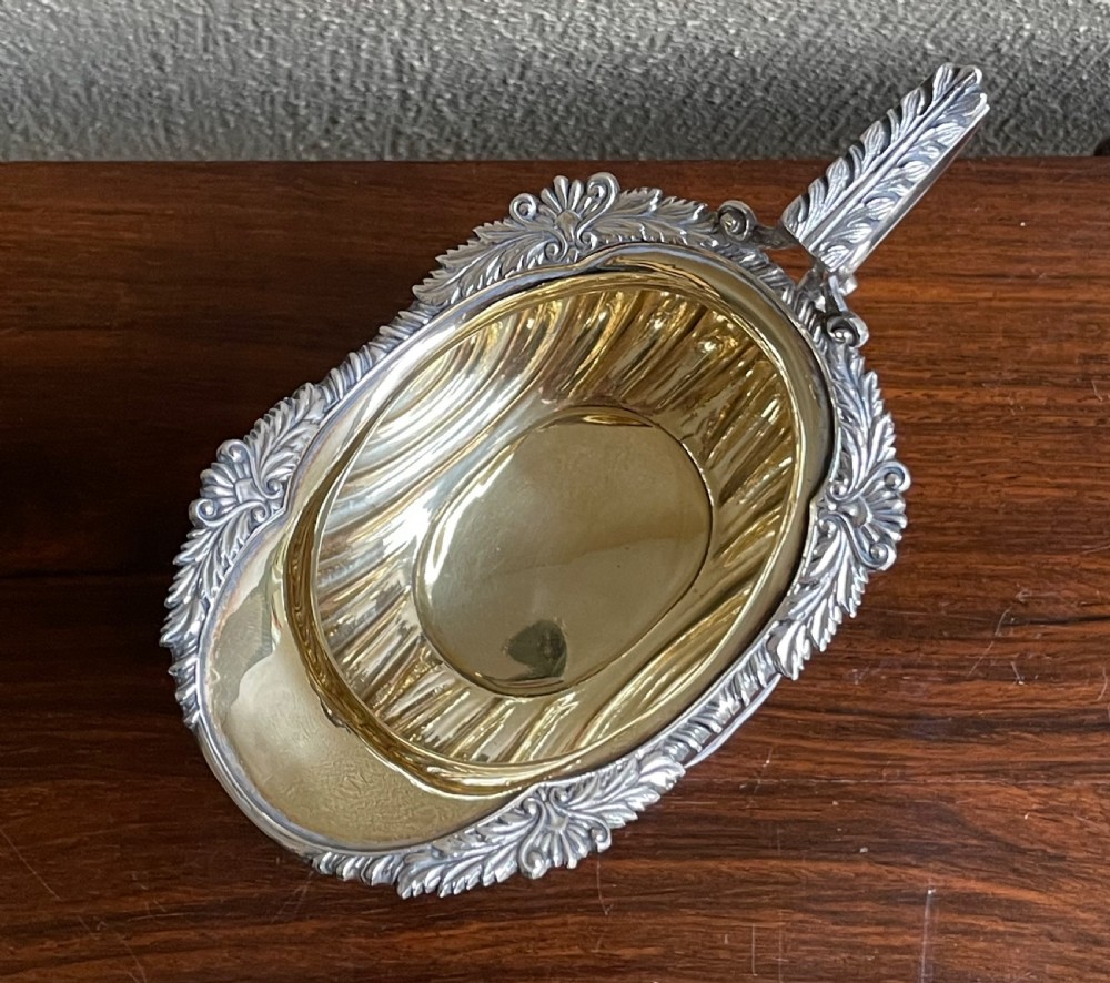 An Edwardian silver cream jug featuring a fluted lower body, cast shell feet, a gadrooned rim, and a gilded interior. View IV