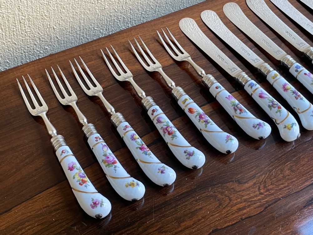 A twelve-piece silver and hand-painted porcelain dessert cutlery set housed in an open oak presentation box lined with blue velvet. View IX