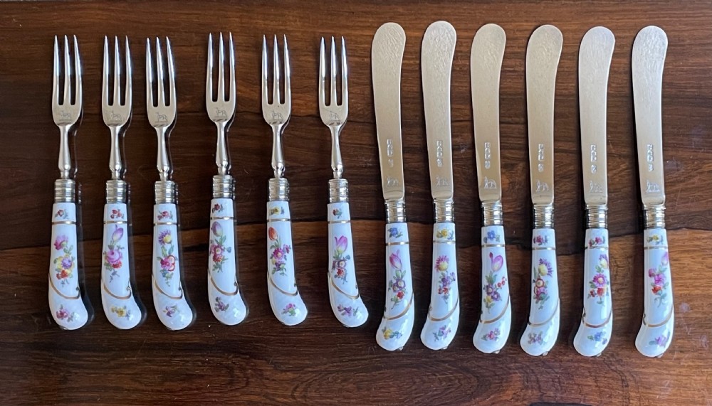 A twelve-piece silver and hand-painted porcelain dessert cutlery set housed in an open oak presentation box lined with blue velvet. View X