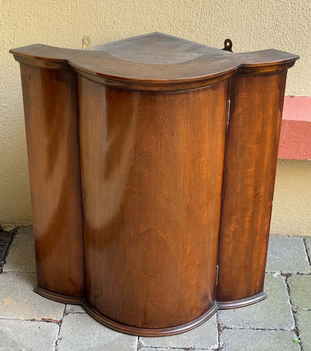 A late nineteenth-century mahogany bowfront corner cupboard with a central curved door and side panels. View III