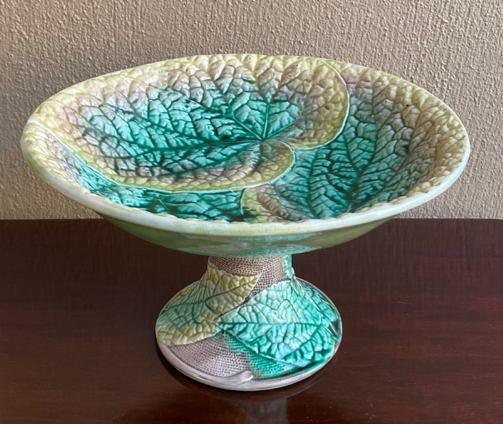 A Victorian majolica pedestal comport bowl featuring moulded green and yellow begonia leaf patterns with a matching leaf-textured stem.