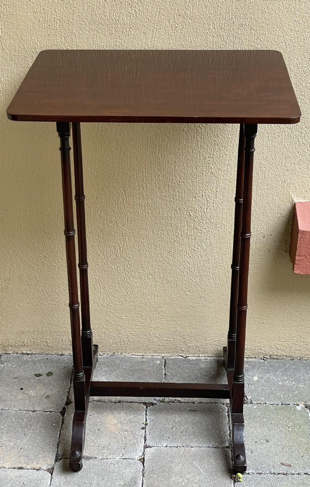 A tall, slender dark mahogany Regency end table featuring a rectangular polished top, turned supports, and a trestle base. View II