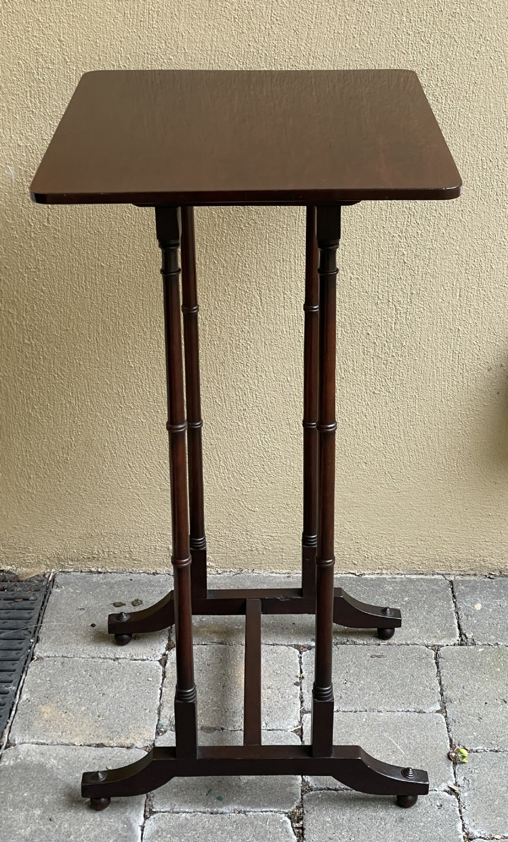 A tall, slender dark mahogany Regency end table featuring a rectangular polished top, turned supports, and a trestle base. View III