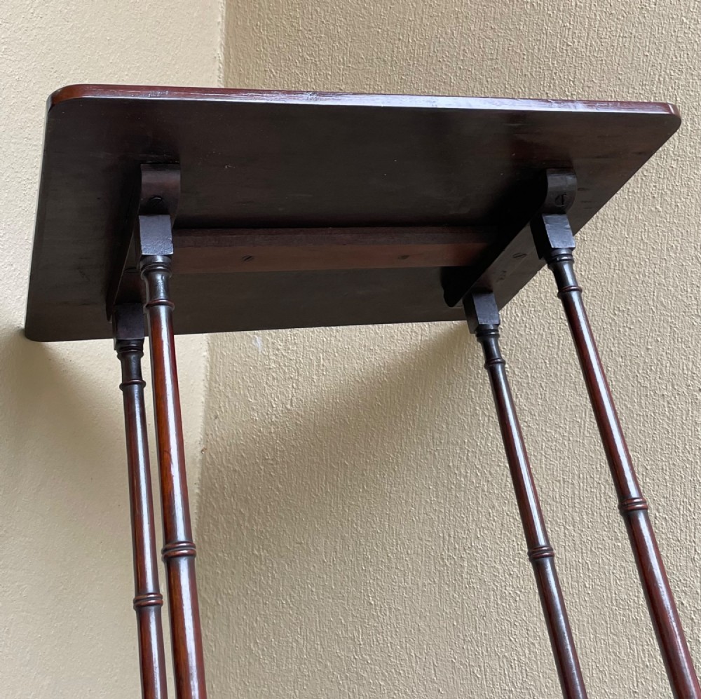 A tall, slender dark mahogany Regency end table featuring a rectangular polished top, turned supports, and a trestle base. View IV