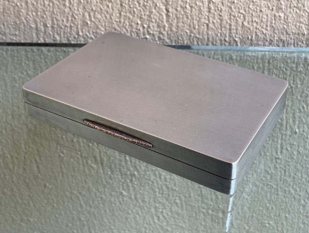 A rectangular Art Deco solid silver table box featuring fine engine-turned engraving, rounded corners, and a textured metal thumbpiece.